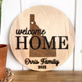 Welcome Home round wood sign with a silhouette of Idaho, featuring the family name and the year. Perfect for hanging in the entryway of a new home